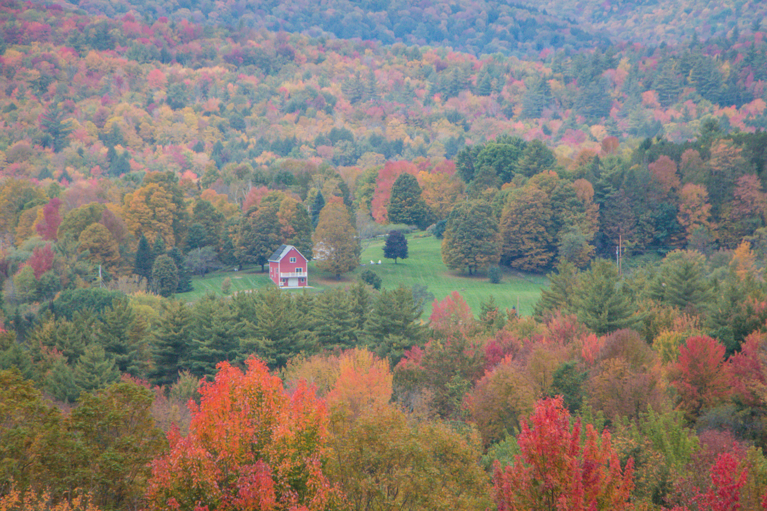 Red building in a clearing among colorful foliage