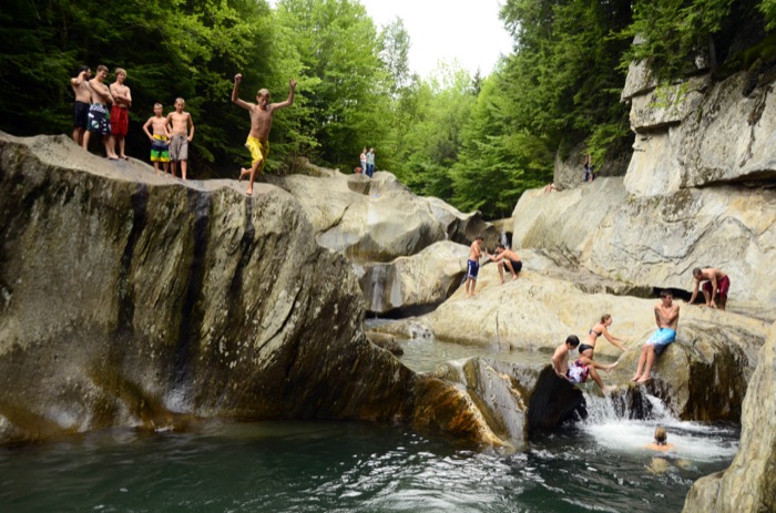 People jumping off rocks into the water below