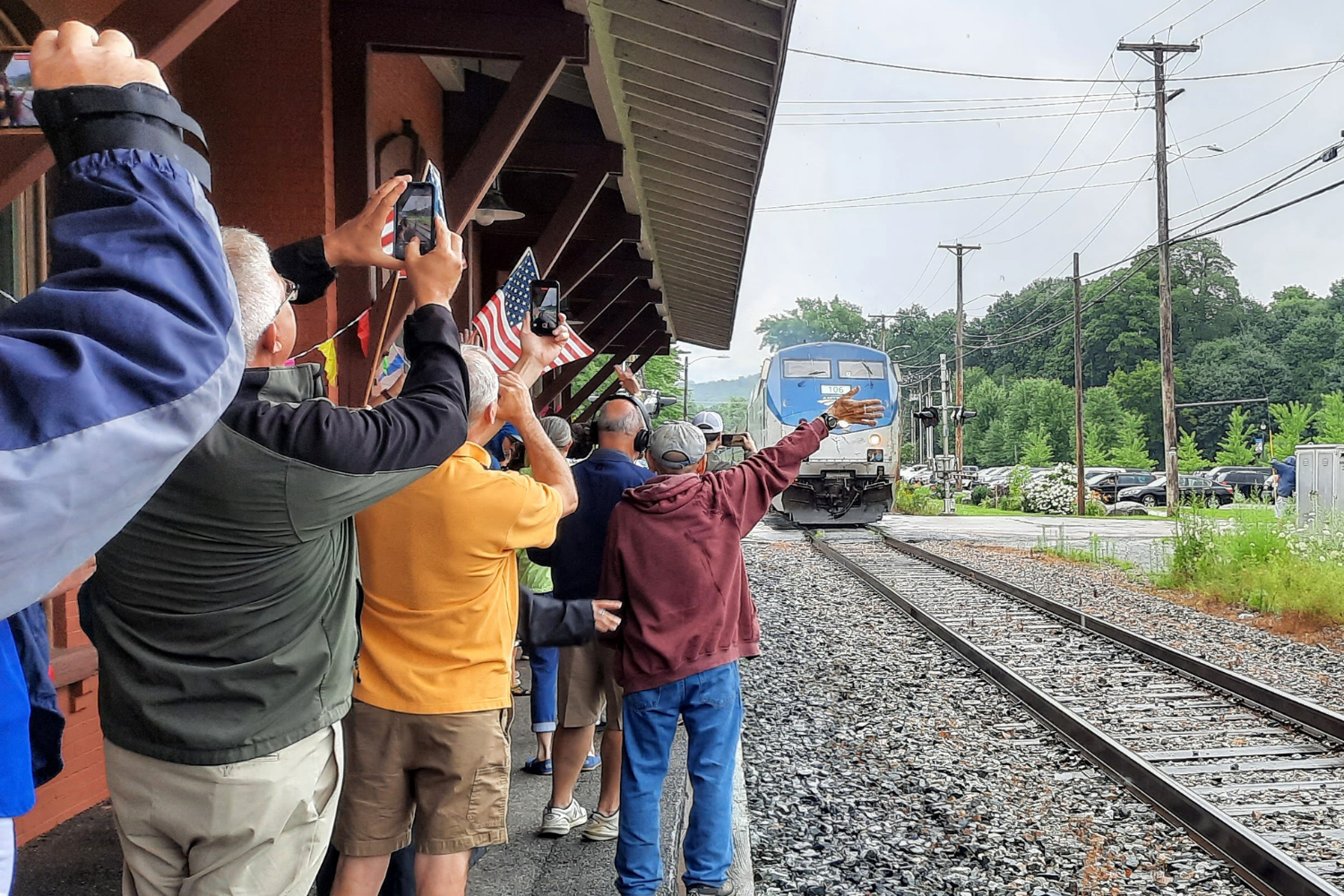 Individuals waving to a train from the Waterbury Station platform